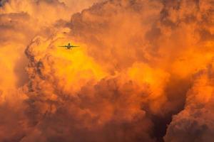 el avión vuela sobre el espectacular cielo naranja y las nubes de fondo abstracto. vista superior de nubes naranjas. imagen artística de textura de nubes naranjas. viaje largo con aerolínea comercial. increíble vuelo al atardecer. foto