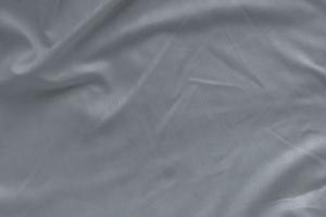 White linen bed sheet texture in hotel bedroom. Closeup detail of messy white bed sheet. Comfortable bed with house dust mite proof sheets. Bedding household concept. Allergen proof microfiber fabric. photo