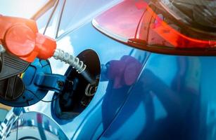 Car fueling at gas station. Refuel fill up with petrol gasoline. Petrol pump filling fuel nozzle in fuel tank of car at gas station. Petrol industry and service. Petrol price and oil crisis concept. photo