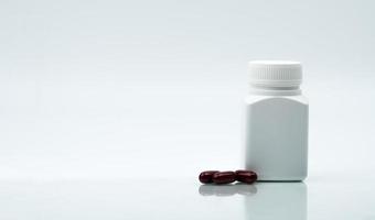 Macro shot of multivitamins capsule pills and closed plastic bottle with blank label and copy space on white background. Vitamins and supplements for hard working guy. Global healthcare concept photo