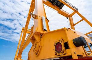 Bottom view of yellow gantry crane against blue sky at port. Gantry crane for cargo and construction industry. Overhead crane for lifting heavy loads. Safety and security working on gantry cranes. photo