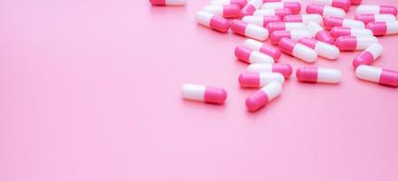 Pink-white antibiotic capsule pills on pink background. Antibiotic drug resistance. Capsule pills spread on pink background. Medication use in hospital. Prescription drugs. Antibiotic drug smart use. photo