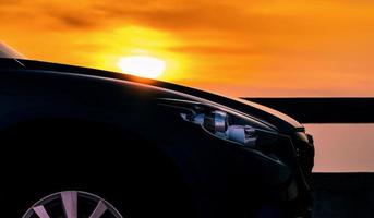 Side view of SUV car with sport and modern design parked on concrete road by the sea at sunset. Hybrid and electric car technology. Travel on vacation at the beach. Road trip. Automotive industry. photo