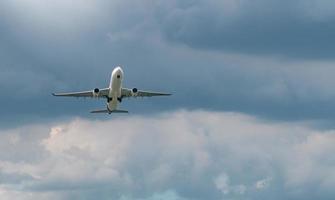 Commercial airline flying on blue sky and white fluffy clouds. Under view of airplane flying. Passenger plane after take off or going to landing flight. Vacation travel abroad. Air transportation. photo