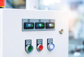 El gabinete del panel de control de temperatura contiene una pantalla digital para medir la temperatura. botón verde, rojo y blanco para abrir, apagar y ajustar la máquina. Control de calor en fábrica industrial. foto