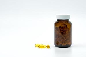 Yellow fish oil capsule pills with amber glass bottle with blank label on the table with copy space for text. Vitamins and supplements for heart care and joint care. Source of omega 3, EPA and DHA. photo