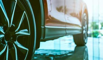 Luxury car parked in modern showroom. Auto leasing business. Car dealership concept. Closeup wheel of red shiny car show in showroom. Automotive industry. Auto glass coating and shinning business. photo