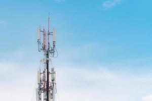 Telecommunication tower with blue sky and white clouds background. Antenna on blue sky. Radio and satellite pole. Communication technology. Telecommunication industry. Mobile or telecom 4g network. photo