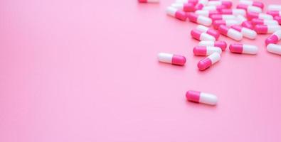 píldora de cápsulas antibióticas rosa-blancas esparcidas sobre fondo rosa. concepto de resistencia a los antibióticos. Uso inteligente de antibióticos. fármaco antimicrobiano. política y presupuesto de salud. industria farmacéutica. foto