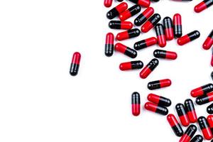 Red-black capsule pills spread on white background. Antibiotic drug use with reasonable. Pharmaceutical industry. Pharmacy background. Global healthcare. Pile of pills with unique pattern texture. photo