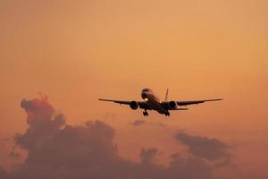 Commercial airline. Passenger plane landing at airport with beautiful sunset  sky and clouds. Arrival flight. Airplane flying in a line for landing. Aircraft open light in the evening flight. photo