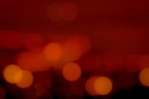 Blurred red and orange bokeh background. Blur abstract background of urban light. Warm light with beautiful pattern of round bokeh. Red light in the night. Street lamp blurred lights. Romantic night. photo