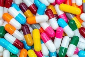 píldoras de cápsulas de colores. industria farmacéutica. antecedentes de salud y medicina. concepto de farmacia. resistencia a los antibióticos. píldoras de cápsula rosa, blanca, naranja, roja, verde, azul y gris. foto