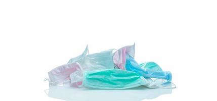 Pile of used surgical face mask isolated on white background. Medical waste. Infectious waste from coronavirus crisis. Pink, green, blue, and white medical face mask waiting for disposal with hygienic photo