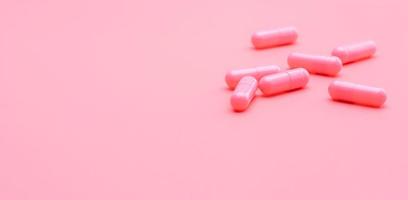 Pink capsules pill on pink background. Vitamins and supplements. Online pharmacy. Pharmacy store banner. Pharmaceutical industry. Woman's health insurance concept. Pills for love and happy life. photo