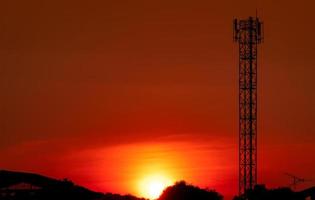 Beautiful red and orange sunset sky. Silhouette telecommunication tower and  tree in the evening with beautiful red sunset sky and clouds. Nature background. photo