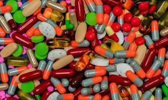 Pile of colorful tablets and capsule pills. Full frame of medicine, vitamins and supplements. Top view many of pills background. Drug, vitamin, supplement and herbal medicine interaction concept. photo