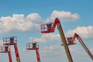 Articulated boom lift. Aerial platform lift. Telescopic boom lift against blue sky. Mobile construction crane for rent and sale. Maintenance and repair hydraulic boom lift service. Crane dealership. photo