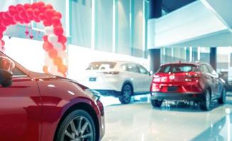 Blurred rear view of red and white luxury SUV car parked in modern showroom for sale. SUV car with sports design in showroom. Car dealership. Coronavirus impact on automotive industry concept. photo