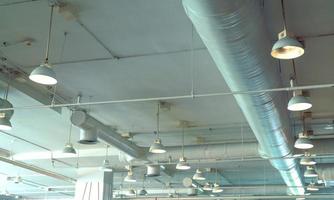 Air duct, wiring and plumbing in the mall. Air conditioner pipe, wiring pipe, and plumbing pipe system. Building interior concept. Ceiling lamp light with opened light. Interior architecture concept. photo