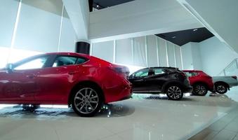 Red and black car parked in modern showroom. Car dealership and auto leasing concept. Automotive industry. Modern luxury showroom. New car parked in showroom. Electric automobile. Showroom interior. photo