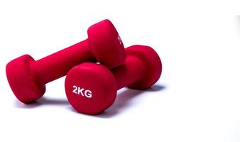 Set of red dumbbells isolated on white background. A pair of red neoprene dumbbells. Home gym equipment for exercise at home. Weight training equipment. Small dumbbells for muscle strength building photo