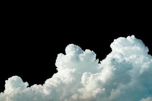Pure white cumulus clouds on black background. Cloudscape background. White fluffy clouds on dark background. Soft cotton feel of white clouds texture isolated on black background with copy space photo