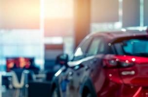 Blurred rear view of red car. Luxury car parked in modern showroom. Car dealership office. Automobile retail shop. Electric and hybrid car business concept. Automobile leasing. Automotive industry. photo