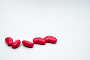 Five red kidney shape sugar coated tablet pills isolated on white background with copy space photo