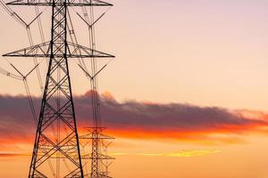 High voltage electric pole and transmission lines in the evening. Electricity pylons at sunset. Power and energy. Energy conservation. High voltage grid tower with wire cable at distribution station. photo