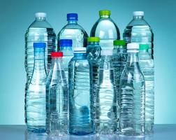 conjunto de botella de agua de plástico transparente con etiqueta en blanco. botella de agua clara y mineral natural con tapa blanca, verde, roja y azul. bebida saludable colección de botella de plástico con líquido completo. foto