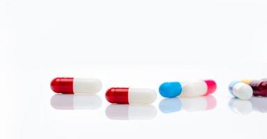 Red-white antibiotic capsule pill on blur multi-colored capsules background. Antibiotic drug resistance concept. Pharmacy horizontal banner. Prescription drugs. Pharmaceutical industry. Healthcare. photo