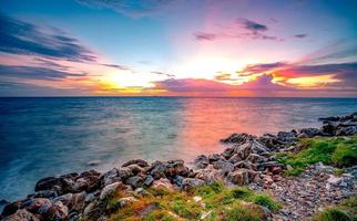 Rocks on stone beach at sunset. Beautiful landscape of calm sea. Tropical sea at dusk. Dramatic colorful sunset sky and cloud. Beauty in nature. Tranquil and peaceful concept. Clean beach in Thailand.