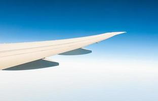 ala de avión sobre nubes blancas. avión volando en el cielo azul claro. vista panorámica desde la ventana del avión. vuelo de aerolínea comercial. ala de avión por encima de la nube. concepto de mecánica de vuelo. Vuelo internacional. foto