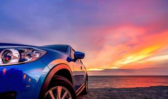 Blue compact SUV car with sport and modern design parked by beach at sunset. Hybrid and electric car technology. Car parking space. Automotive industry. Car care business background. Beautiful sky. photo
