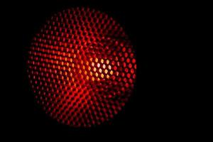 Closeup honeycomb grid texture with red light. Red and dark metal hexagon shaped pattern abstract background. Light modifier equipment. Metal honeycomb. Futuristic pattern. Honey grid cells network. photo