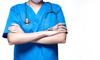 el médico o la enfermera asiáticos usan uniforme azul con estetoscopio. médico de pie con los brazos cruzados aislado sobre fondo blanco. profesional de la salud. concepto de seguro de salud. médico experto. foto