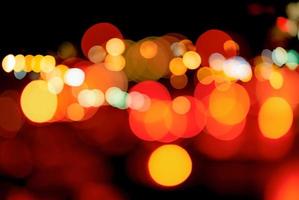 Blurred red and orange bokeh background. Blur abstract background of urban light. Warm light with beautiful pattern of round bokeh. Light in the night. Street lamp lights in the city at dark night. photo