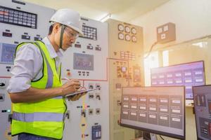 Engineer working on the checking status switchgear electrical energy distribution substation. Electrician and tool logging information in electrical switch room. photo