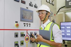 Engineer working on the checking status switchgear electrical energy distribution substation. Electrician and tool logging information in electrical switch room. photo