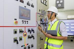 Experienced electrician working in power plant control room. Engineer working on the checking status switchgear electrical energy distribution substation. photo