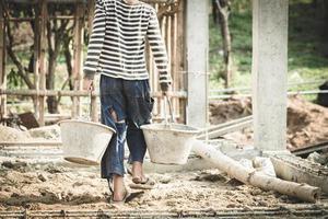 los niños que trabajan en las obras de construcción se ven obligados a trabajar. el concepto de lucha contra el trabajo infantil. el abuso del trabajo. la opresión o intimidación del trabajo forzoso entre los niños. foto