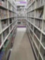 pasillo borroso de libros dispuestos en estanterías, estantería en la tienda o en la biblioteca, fondo foto