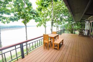 Wooden table and chairs on balcony and nature green tree forest balcony view river terrace house photo