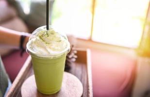 batido de té verde - té verde matcha con leche en vaso de plástico servido en una cafetería foto