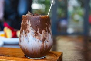 cocoa drink and chocolate - tasty milk shake with ice cocoa in glass on wood background photo