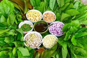 Miang Kham Or wild betel leaves wrap ingredients with lemon grass, garlic, shallot, lime, chilli, roasted peanuts with sweet dipping sauce, Asian appetizer food. photo