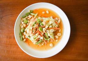 Thai food papaya salad with macadamia nuts on top on white plate Healthy food photo