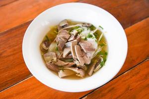 Tazón de fideos deliciosos - sopa de fideos vermicelli con vegetales estofados de cerdo en un tazón comida tradicional tailandesa y china de asia, despojos de cerdo, intestinos de hígado de cerdo foto