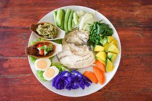 Thailand food Asian cooked tilapia fish - Steamed fish with chili sauce boiled eggs and vegetables pumpkin carrot on white plate photo